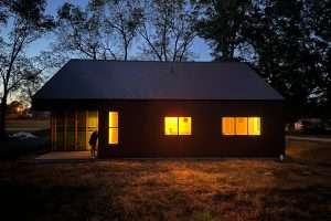 A photo of the house's windows glowing at night.